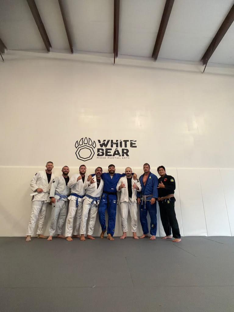 White Bear MMA gi class in front of the logo wall
